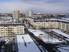 Barevná fotografie s pohledem na zasněženou městskou oblast s panelovými domy