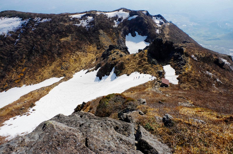 岩木山の雪渓を歩く人々の写真