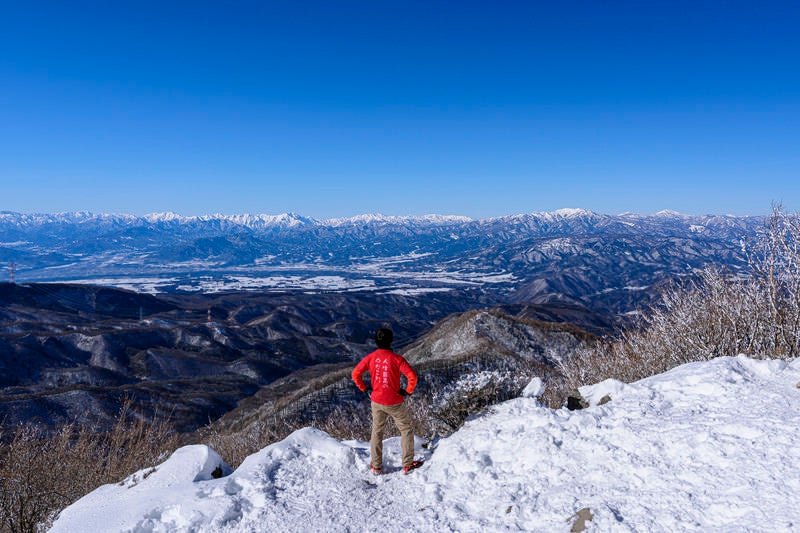 赤城山で仁王立ちする赤い登山者の写真