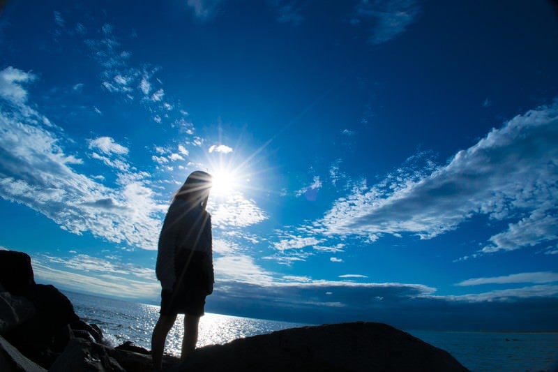 海岸に立つ女性のシルエットの写真