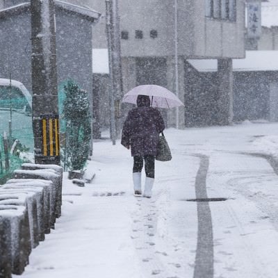 降雪の道路に残る足跡とタイヤ痕の写真