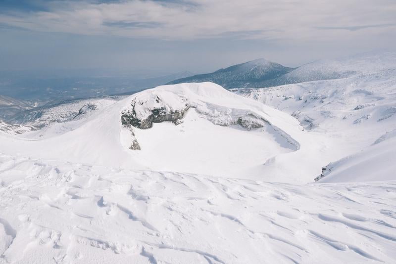 御釜火口湖とその雪に覆われた景色の写真