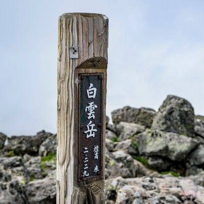 背景に雲が目立つ大雪山白雲岳の木碑の写真