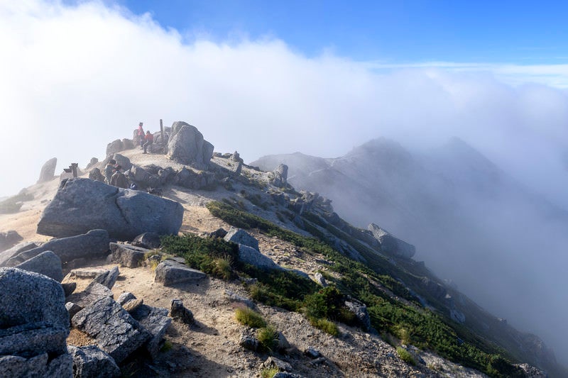 晴れた山頂に湧き上がる登山者と空木岳山頂の写真