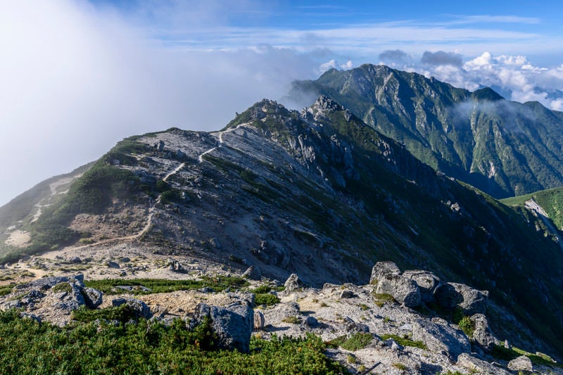 雲が流れゆく南駒ヶ岳方面の登山道の写真