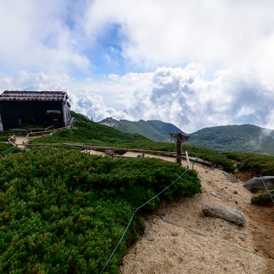 雲と青空に包まれる駒峰ヒュッテ（空木岳）の写真