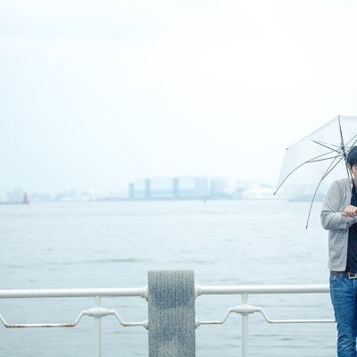 雨の日の初デート、時間を確認するしぐさで高鳴りをごまかす男性の写真