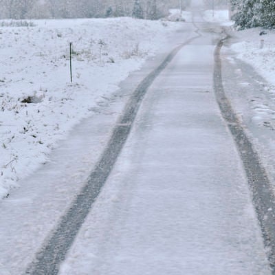 人のいない雪道と車の痕の写真