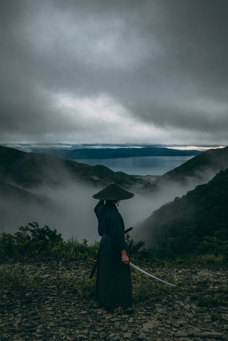 迫りくる灰色の雲と刀を抜いた侍の写真