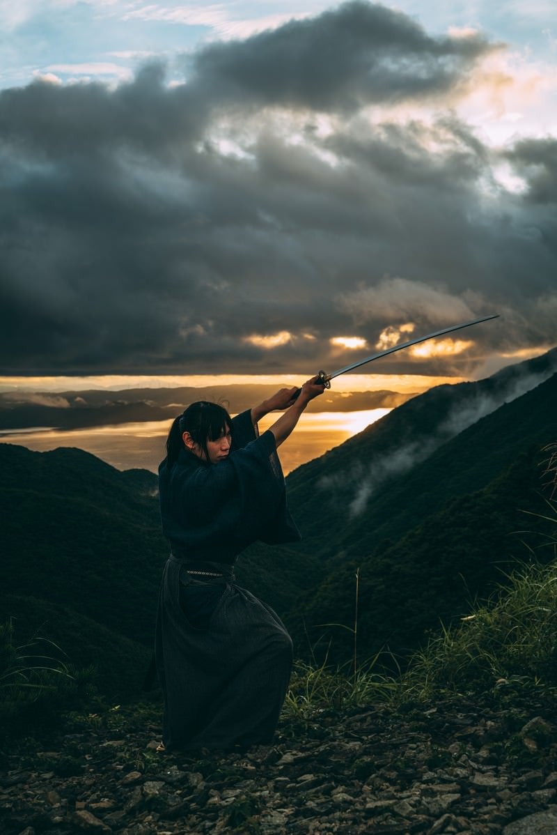 日本刀で切り上げる侍と夕景の写真