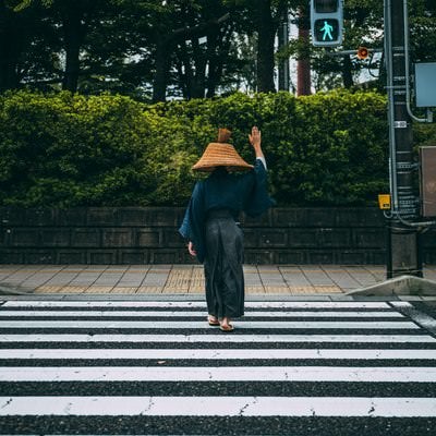 手を上げて横断歩道を渡る網代笠侍の写真