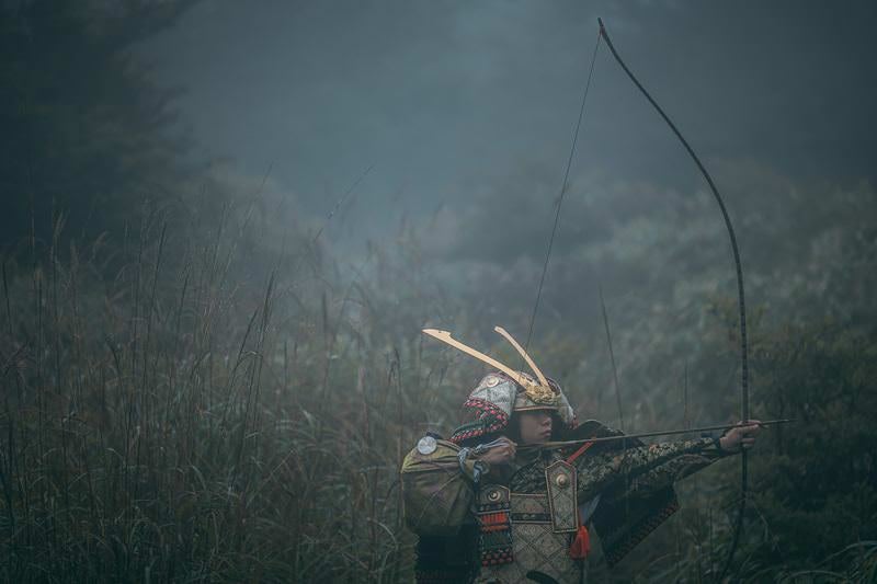 霧に紛れて大弓を引く武将の写真