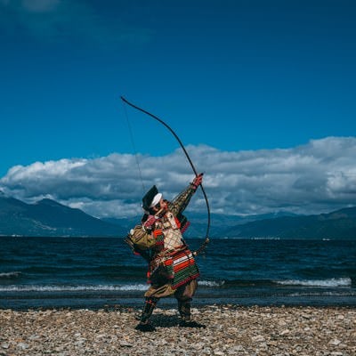 空に向かって大弓を放つ侍の写真