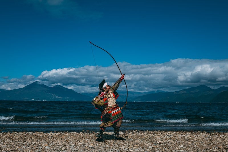 空に向かって大弓を放つ侍の写真