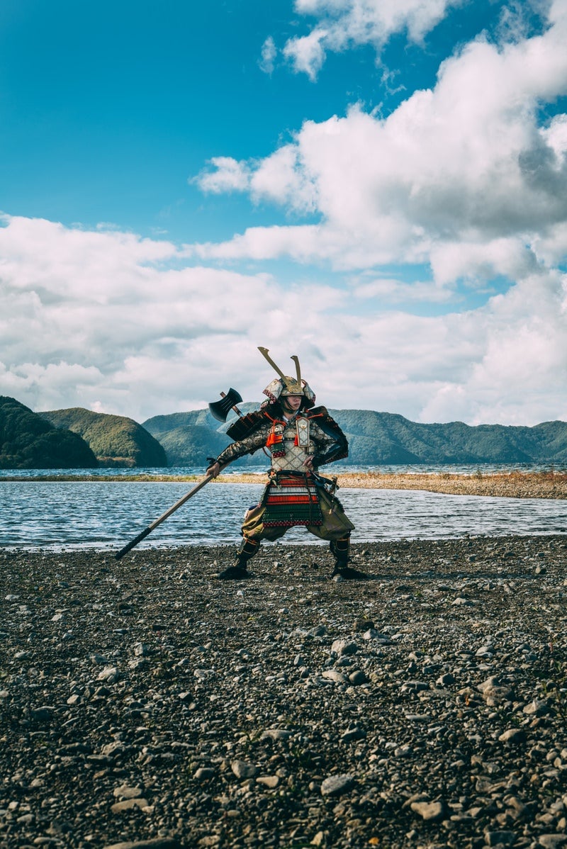 「棍棒を大きく振りかぶる鎧を纏った武将」の写真［モデル：まーこ］