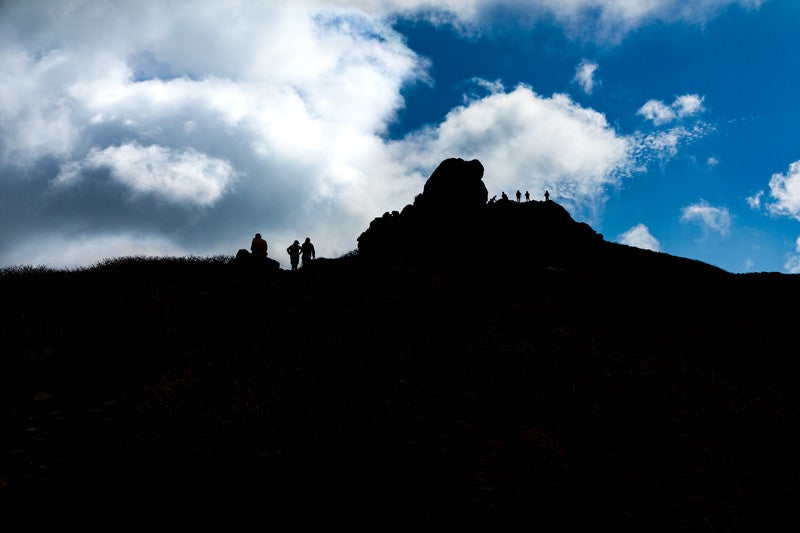 山頂に並ぶ登山者達のシルエットと沸き立つ雲（三ツ石山）の写真