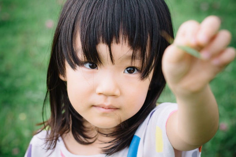 公園でバッタを見つけた少女の写真