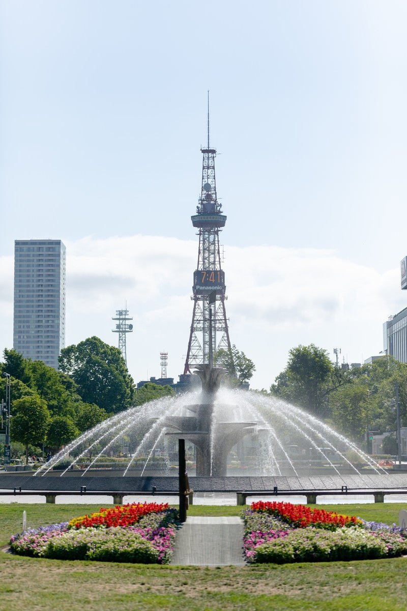 噴水越しのさっぽろテレビ塔（大通公園）の写真