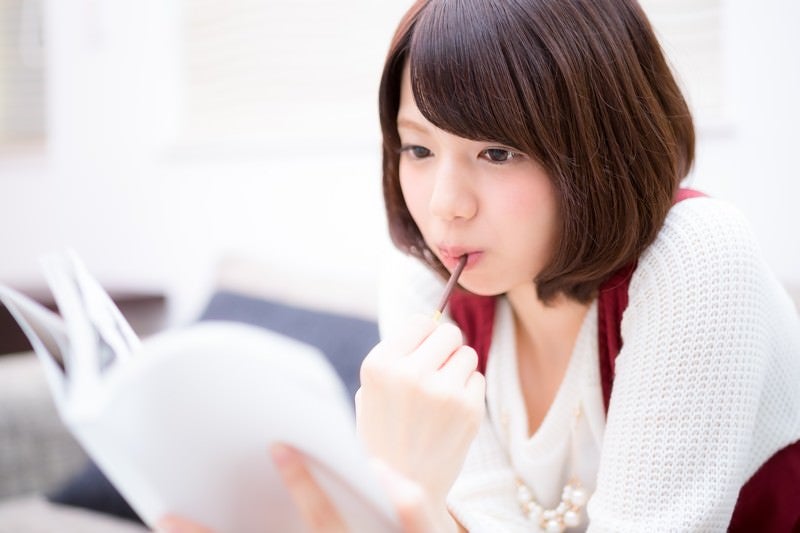 休日、マンガを読みながらお菓子を食べる美女の写真