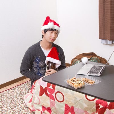 クリスマスに寂しく一升瓶を抱える男性の写真