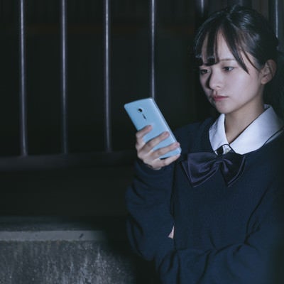 スマホを使って追跡調査する女子高生探偵の写真