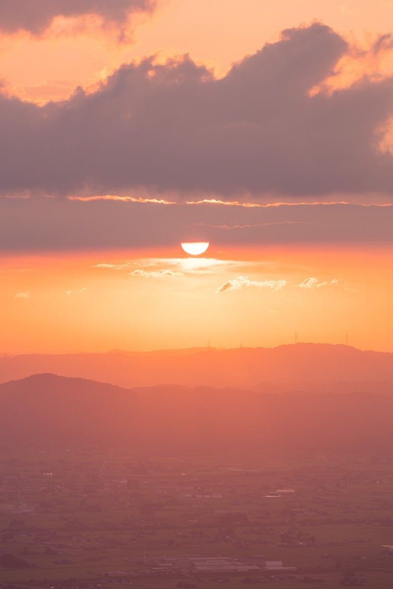 沈む夕日と散居村（富山県南砺市）の写真