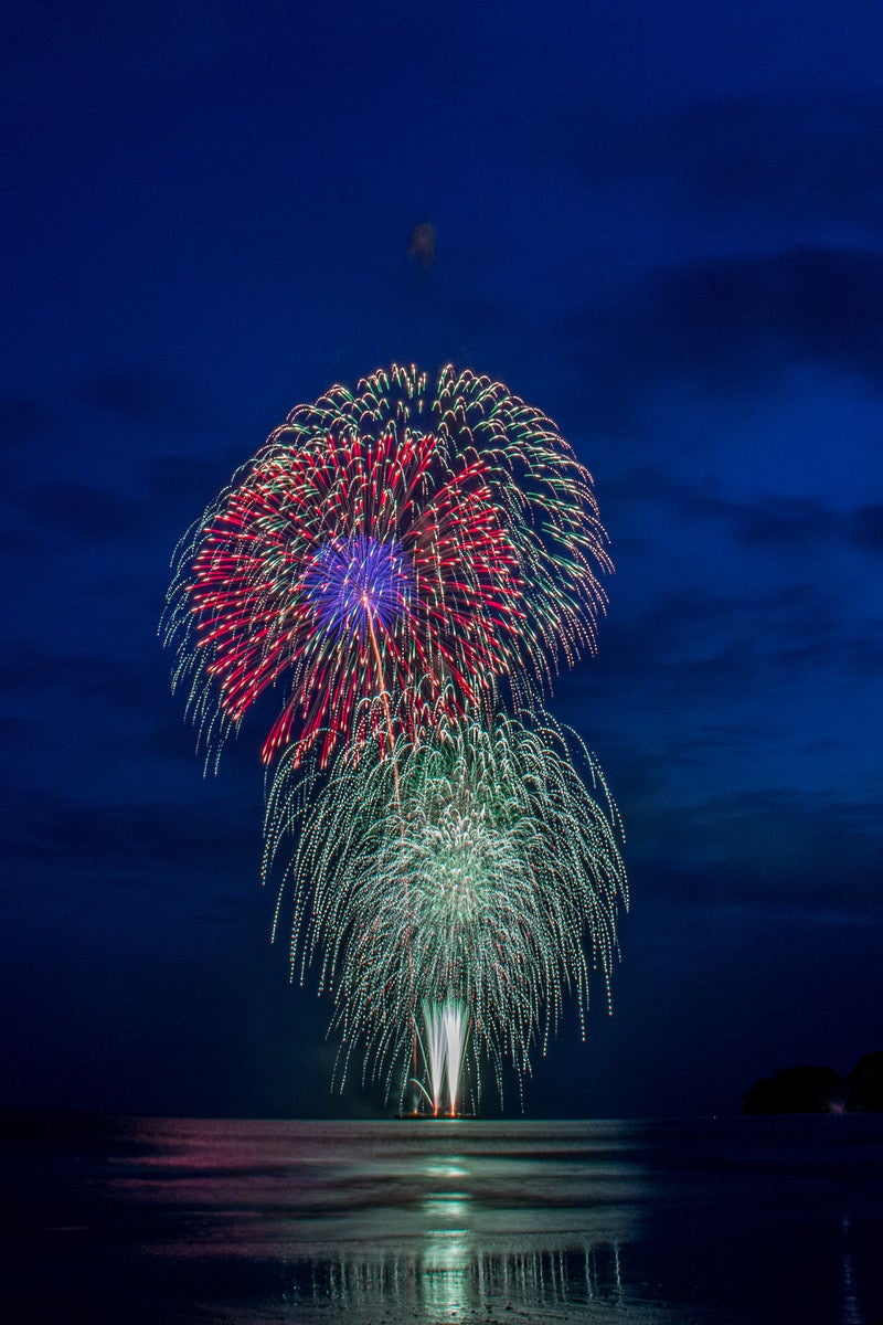 海上で打ち上げられるスターマイン花火の写真