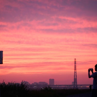 夕焼け空を撮影する少年の写真