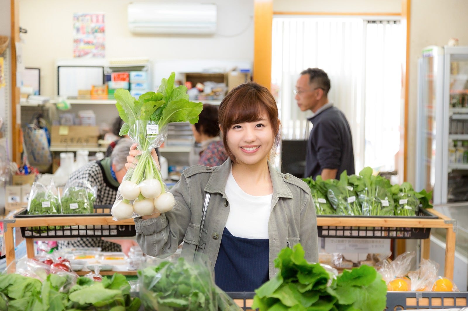 「「株あがれー」の笑顔で店主のお株を奪う女性観光客とふれあい市場の様子」の写真［モデル：河村友歌］