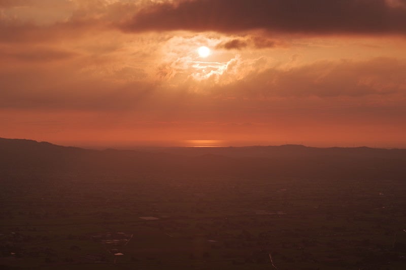 夕暮れに染まる雲間から見える太陽（富山県南砺市）の写真