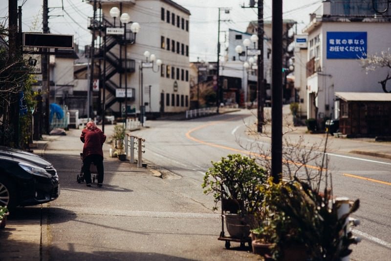 閑散とした街と老婆の後ろ姿の写真