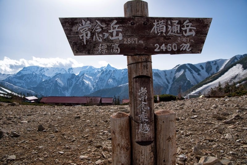 常念乗越の看板と山小屋から望む山峰の写真