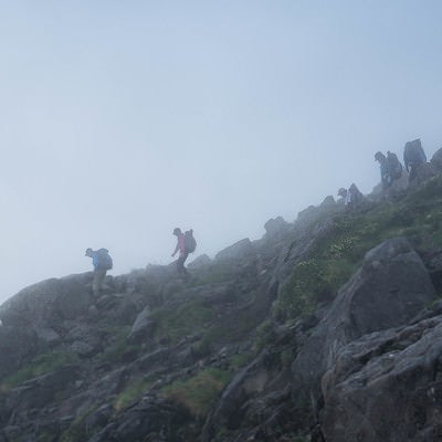 視界不良の霧の中を下山する登山者の写真