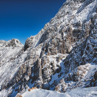 雪が降った後の青空と赤岳の岩壁（八ヶ岳連峰）の写真