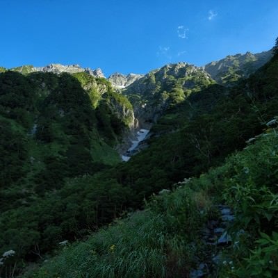 山間に見える吊尾根の岩壁の写真