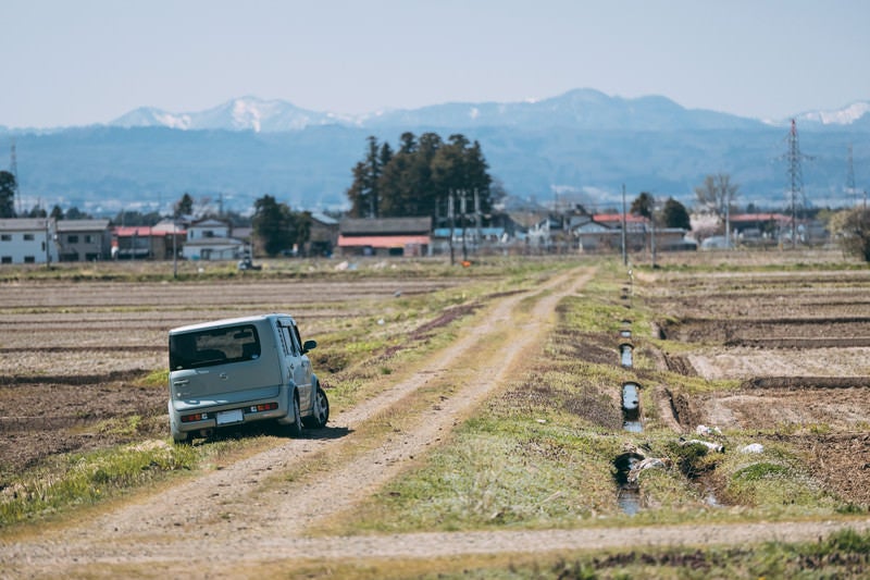 あぜ道で脱輪する車の写真