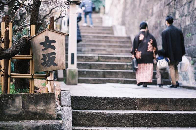 湯島天神の女坂をのぼる親子の後ろ姿の写真