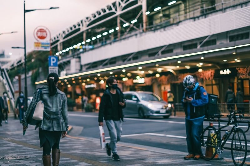 駅前の歩道を行き交う通行人の写真