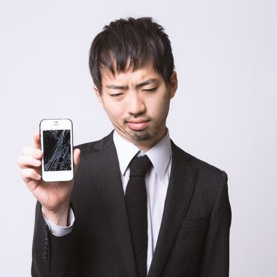 スマートフォンを落としてガックリしている男性の写真