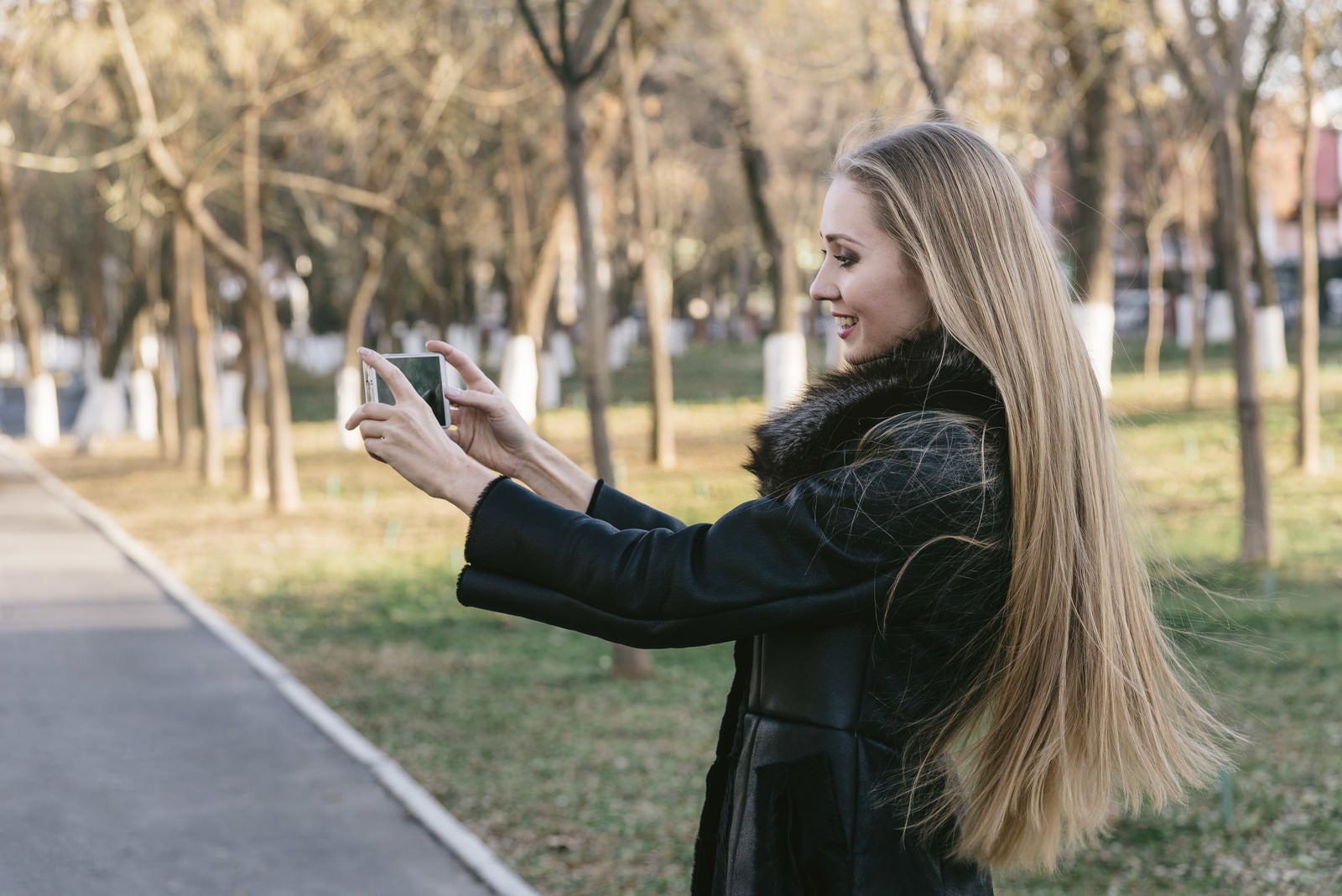 「公園をスマホで撮影するモデル」の写真［モデル：モデルファクトリー］