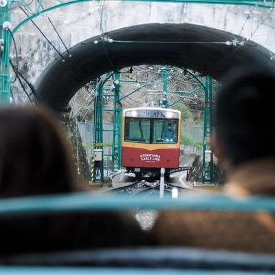 トンネル越しに見る接近中のケーブルカー（鋼索線客車）の写真