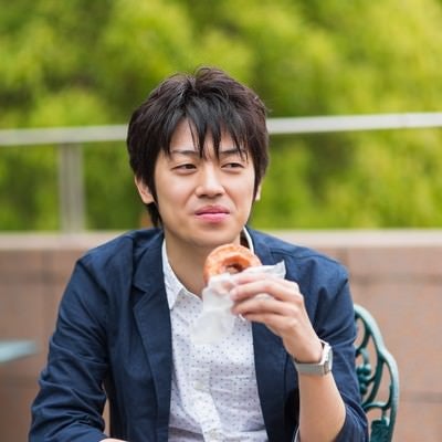 テーブルでドーナツを食べる男性の写真