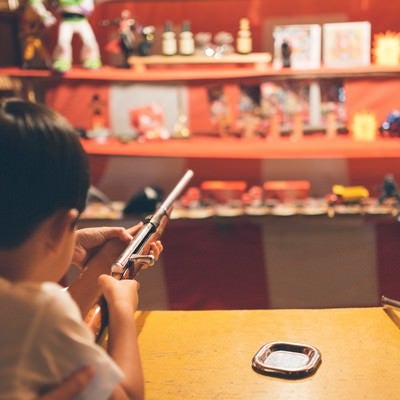 お祭りの出店にある射撃で銃を構える子供の写真