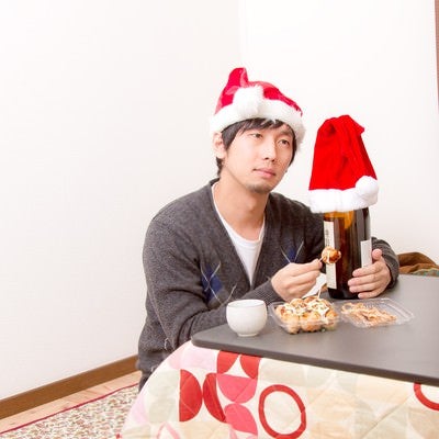 コタツで寂しくクリスマスを過ごす男性の写真