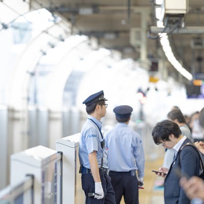 電車を待つ人と駅員の写真