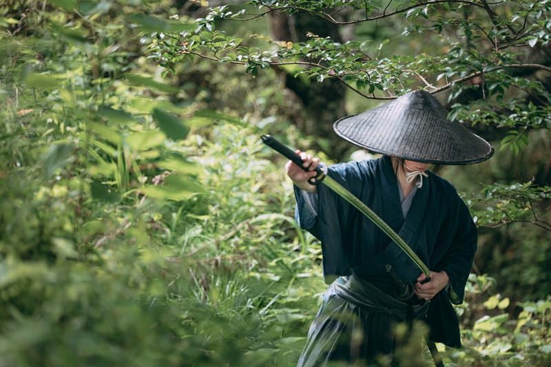 藪に隠れて刀を収める侍の写真