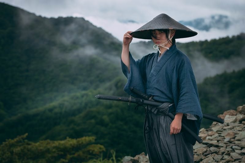 網代笠に右手を添える袴姿の侍の写真