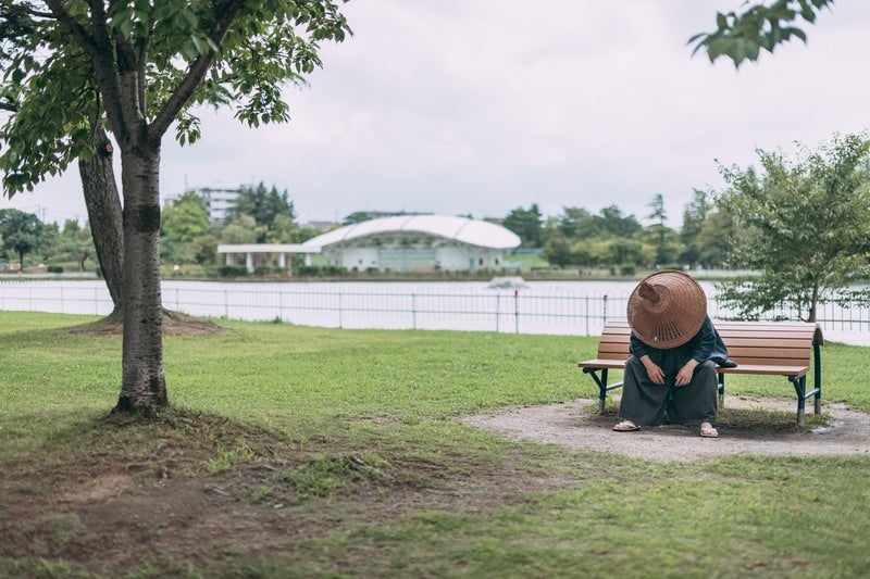 公園のベンチで項垂れる侍の写真