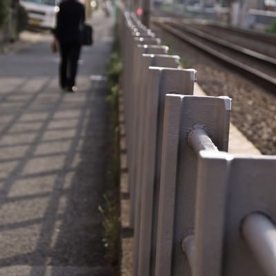 線路沿いを歩くサラリーマンの写真