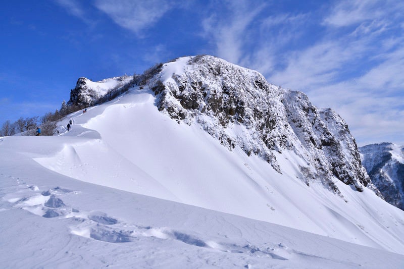 冬の断崖絶壁に挑む登山者と足跡の写真